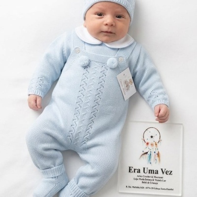 Bebé vestido com fato de malha azul clara com gorro de malha