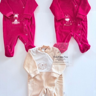 Três pijamas de veludo para bebé nas cores rosa e bege com bordados de girafa e urso.