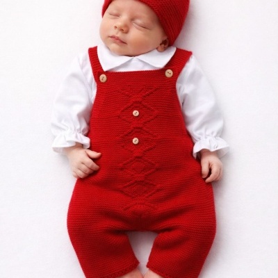 Bebé vestido com macacão vermelho de malha e gorro vermelho com pompom