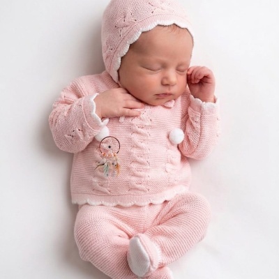 Bebé vestido com roupa de malha rosa com capuz e decoração de filtro dos sonhos