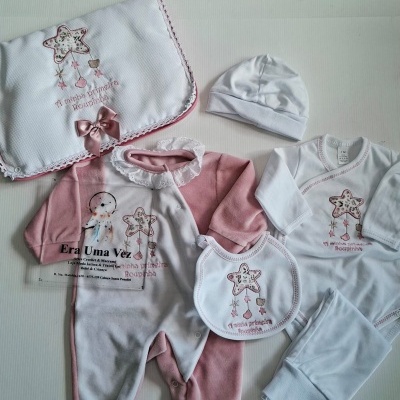 Conjunto de roupa de bebé rosa e branco com estampados de estrela e texto bordado numa manta