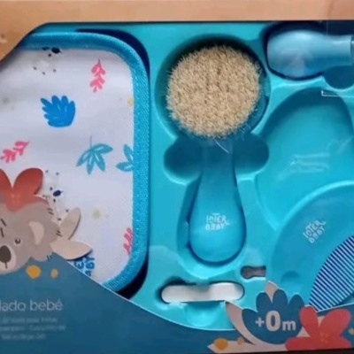 Conjunto de cuidado para bebé azul com escova, pente, toalha estampada e tesoura numa embalagem