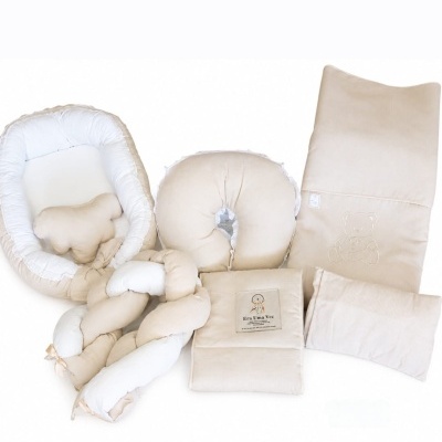 Acessórios para bebé em bege e branco, com almofadas, manta e ninho para bebé.