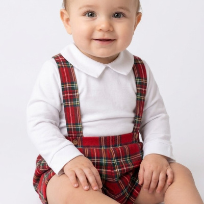 Bebé sentado com roupa de tartan vermelho e body branco