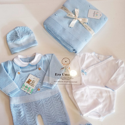Conjunto de roupa de bebé azul e branco com manta e acessórios sobre fundo branco.