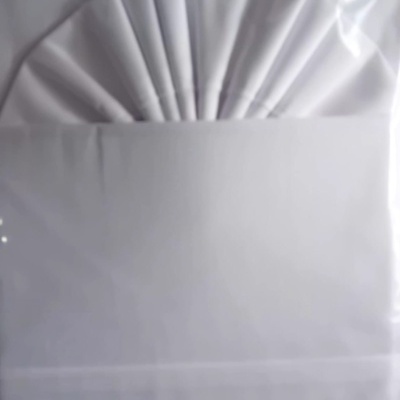 Conjunto branco de lençóis embalado em saco plástico.