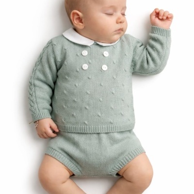 Bebé deitado vestido com camisola e calções verdes de malha