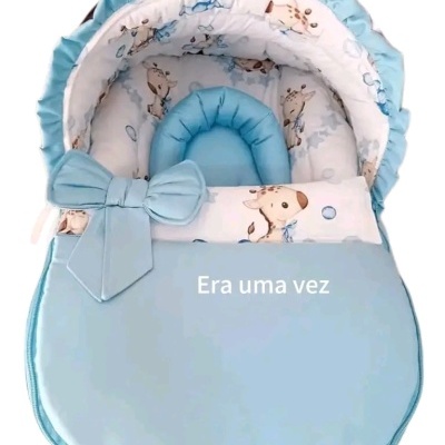 Alcofa de bebé azul com padrão interior de girafas e lacinho azul