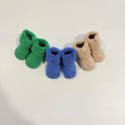 Três pares de pantufas infantis em tecido felpudo verde, azul e bege