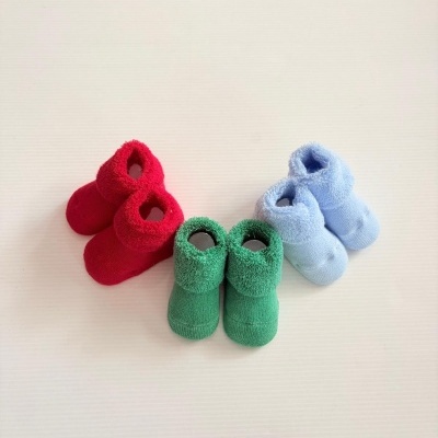 Três pares de meias para bebé em vermelho, verde e azul claro com textura felpuda na parte da gola