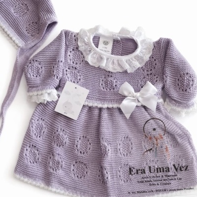 Vestido e touca lilás de malha para bebé com gola branca de renda e laço, etiqueta com texto 1/3M 100% Algodão, fundo branco com texto Era Uma Vez