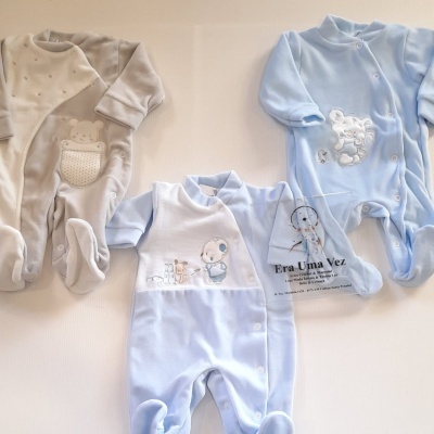 Três macacões de bebé em veludo cinza e azul com bordados de ursinhos, dispostos em fundo branco.