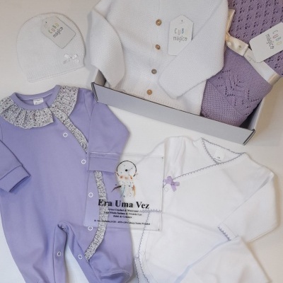 Conjunto de roupas de bebé lilás e branco com etiqueta Cubo mágico sobre fundo branco