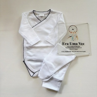 Body branco para bebé com borda preta e calças brancas, junto a placa transparente com texto da loja Era Uma Vez