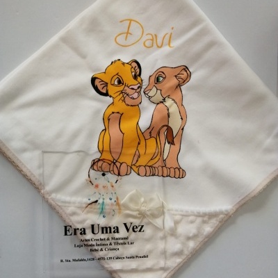Manta branca com estampa Simba e Nala com nome Davi e texto de loja na parte inferior