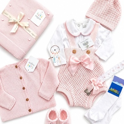 Conjunto de roupa rosa e branca para bebé com peças de malha, body e acessórios.