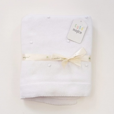 Manta branca tricotada com pompons e etiqueta CUBO mágico