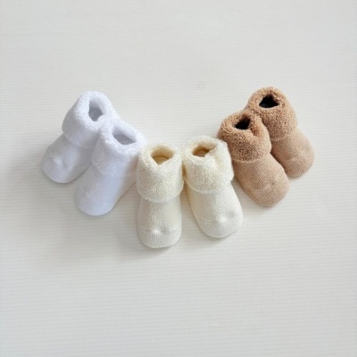 Três pares de meias tipo botins para bebé em branco, bege claro e castanho.
