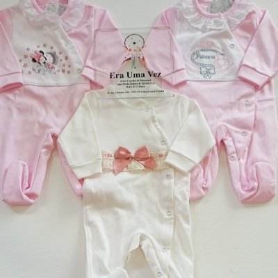 Três macacões de bebé em algodão, rosa e branco, com detalhes de babado, estampas e laço