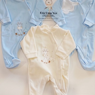 Três macacões de bebé em azul e branco com bordados de girafa e placa com texto Era Uma Vez