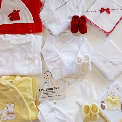 Conjunto de roupa para bebé com bodies, casacos, sapatinhos e mantas em várias cores e texturas.