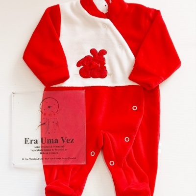 Pijama bebé vermelho com coelhinhos vermelhos e parte branca, com botões de pressão e livro com texto em português.
