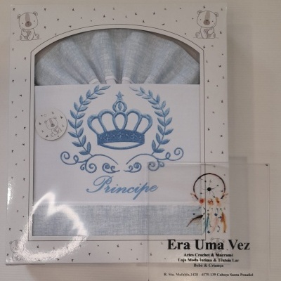 Caixa com cobertor cinzento estampado com coroa azul e palavra Príncipe, decorada com ursos e estrelas.