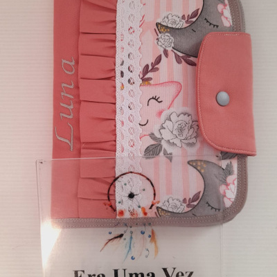 Capa de tecido rosa para livros com padrão de luas e flores e o nome Luna bordado.