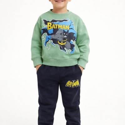 Menino com conjunto de roupa infantil verde e azul com estampado Batman e sapatilhas brancas