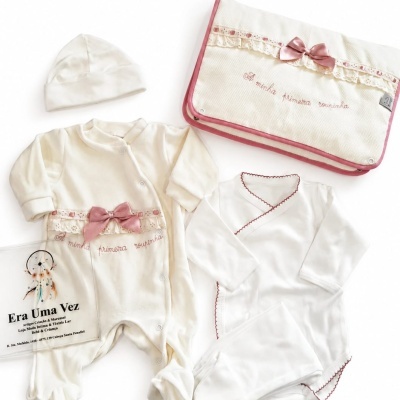 Conjunto de roupa de bebé branco com detalhes em rosa e bolsa com bordado