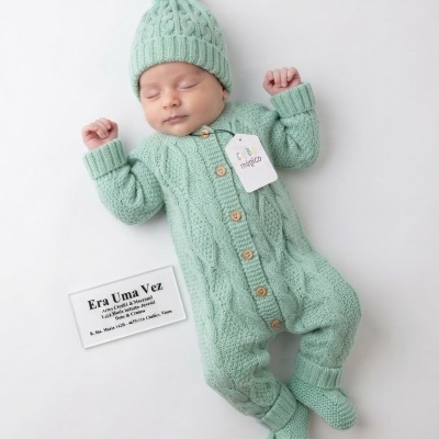 Bebé vestido com fato de malha verde água trançado e chapéu com pompom