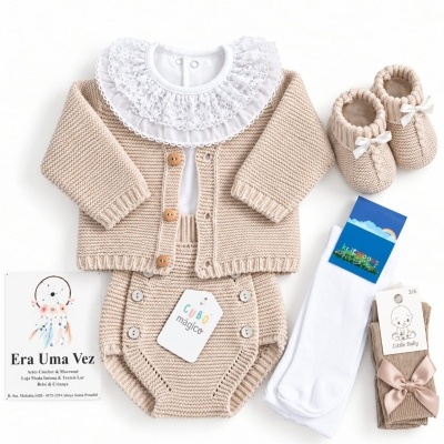Conjunto de roupa de bebé em malha bege com casaco, body com gola de renda branca, botinhas de tricô, meias e etiquetas.