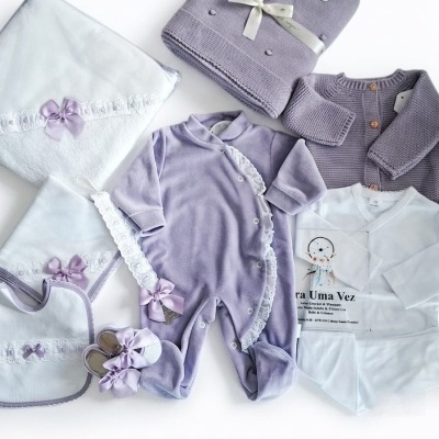 Conjunto de roupa e acessórios de bebé lilás e branco com detalhes em laço