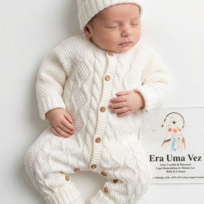 Bebé a vestir roupa de malha branca com gorro e meias brancas