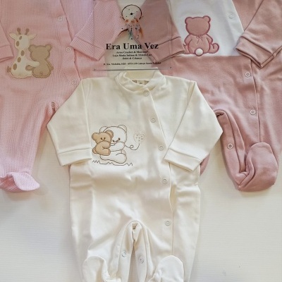Três macacões de bebé em tons de branco e rosa com aplicações de ursinhos e fechos de mola.