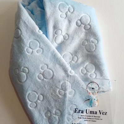 Manta de bebé azul clara com padrão em relevo de círculos e placa transparente com texto da marca.