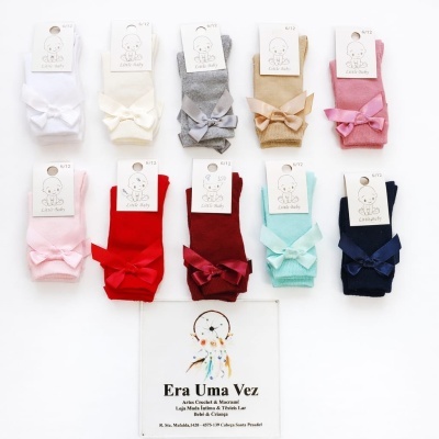 Dez pares de meias de bebé coloridas com laços, logo Little Baby, e placa da loja Era Uma Vez