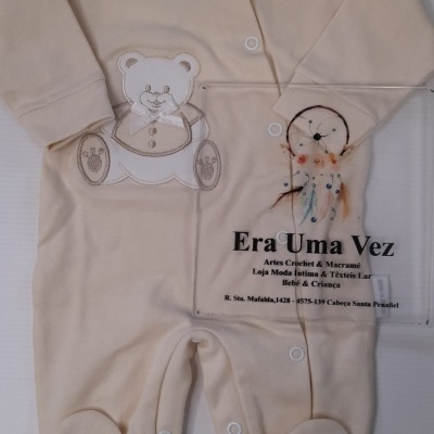 Macacão creme de bebé com bordado de ursinho e etiqueta com texto da loja Era Uma Vez