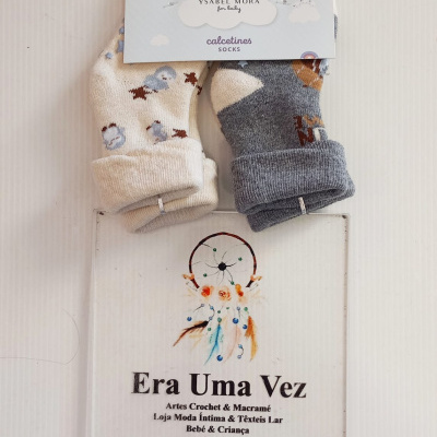 Par de meias de bebé, bege e cinzento, com padrões, embaladas com papel azul com nuvem e texto