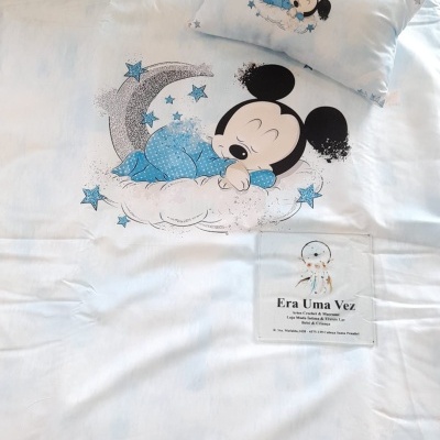 Roupa de cama infantil com desenho de Mickey a dormir numa nuvem e estrelas, fundo branco.
