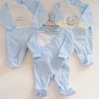 Três macacões de bebé azul claro e branco com bordados e botões, sobre fundo branco