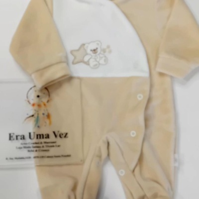 Macacão de bebé bege e branco com ursinho e estrela, em tecido macio.
