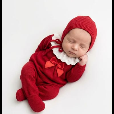 Bebé a dormir vestido com macacão vermelho e gorro vermelho