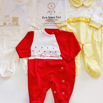 Três pijamas de bebé em branco, amarelo e vermelho com diferentes padrões e texturas
