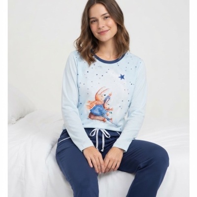 Pijama feminino azul com estampa de coelhinhos e estrelas, à mulher sentada na cama
