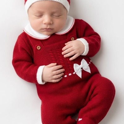 Bebé deitado com fato de malha vermelho e branco e gorro vermelho com borda branca