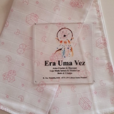 Toalha branca com padrão infantil rosa e etiqueta transparente colorida com texto em português