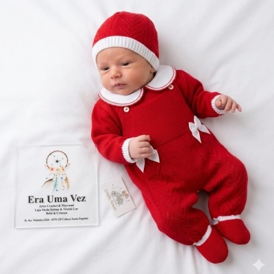 Bebé com roupa vermelha tricotada, gorro e sapatinhos, sobre fundo branco