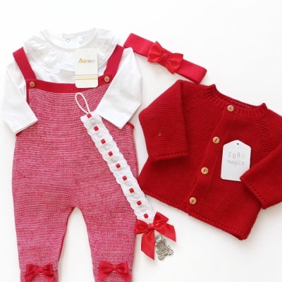 Conjunto de roupa para bebé com jardineiras vermelhas, camisola branca e casaco vermelho.