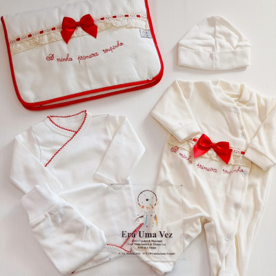 Conjunto de roupa de bebé branco com detalhes em laço vermelho e bolsa decorada